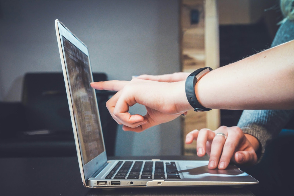 A close-up of two people pointing to a laptop screen